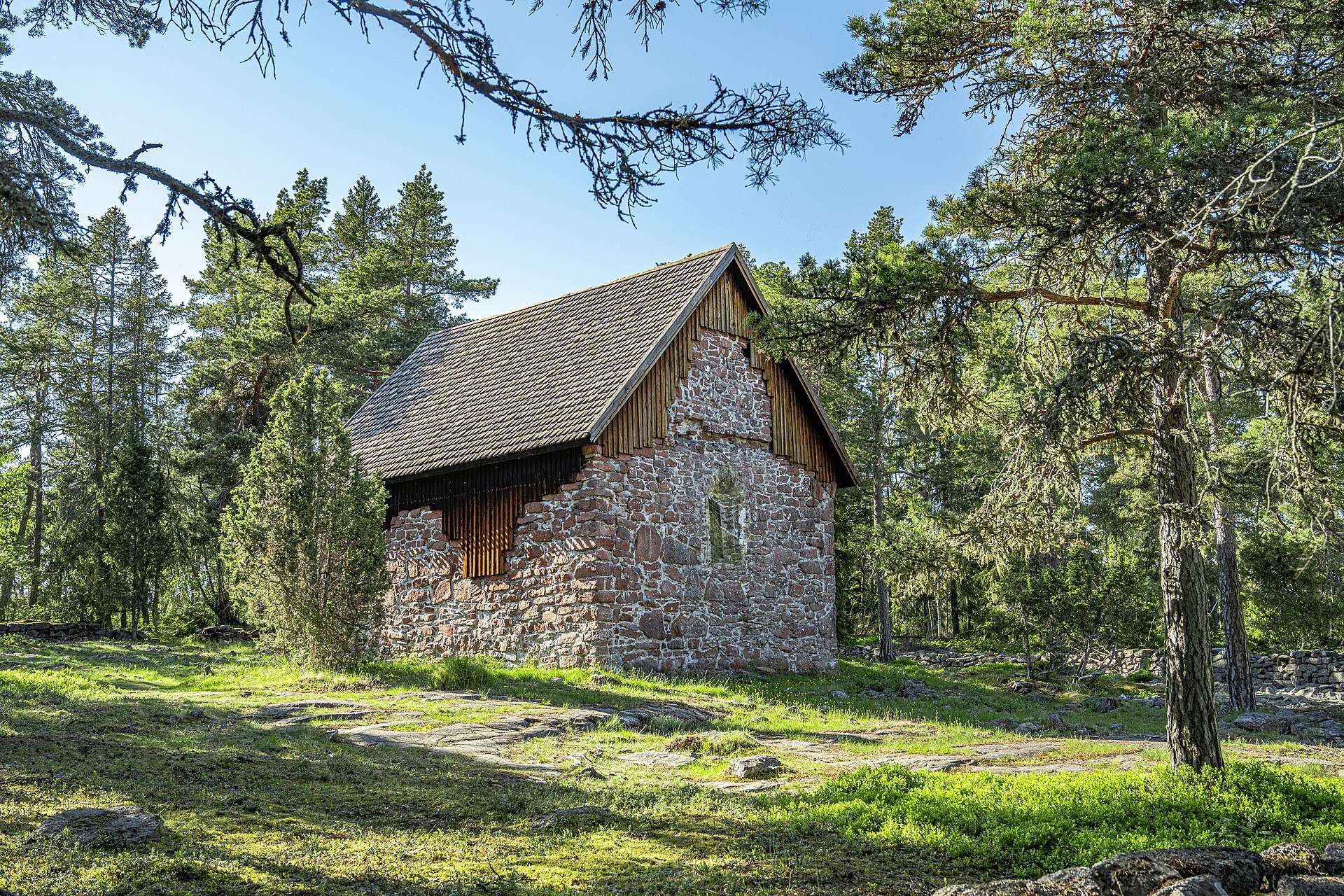 Lemböte kapellruin av sten bland tallar